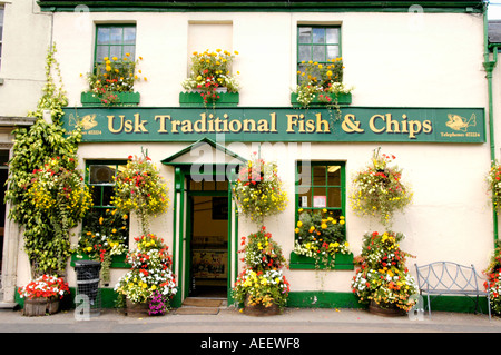 Display floreale al di fuori del USK il tradizionale pesce e patatine il negozio nella città rurale di Usk Monmouthshire South Wales UK Foto Stock