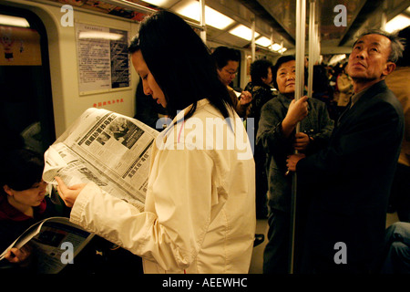 Shanghai China Shanghai sistema di metropolitana è moderno e swift una donna legge un giornale in un affollato carrello Foto Stock