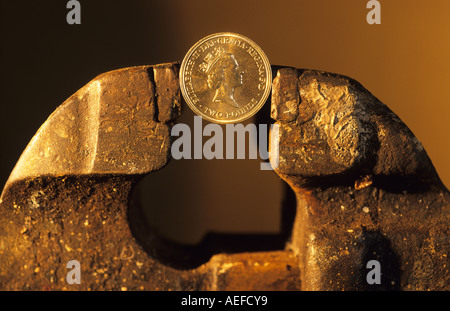 Sterlina inglese due pound coin essere schiacciati nelle ganasce della morsa Foto Stock