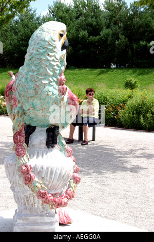 Senior lady un visitatore stanco appoggiato accanto al castello di Nymphenburg statua di porcellana a giardino mostra Muenchen Monaco di Baviera Baviera Germania Foto Stock