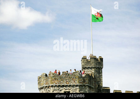 I turisti si raccolgono sotto il Welsh bandiera nazionale battenti sulla sommità della famosa attrazione turistica di Castello di Cardiff Cardiff Wales UK GB Foto Stock