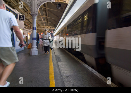 Orizzontale di ampio angolo di gente correre per prendere un treno in arrivo alla piattaforma. Foto Stock