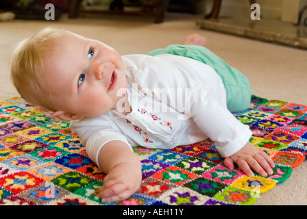 Chiudere orizzontale su ritratto di un periodo di sei mesi di età caucasian Baby girl rotolando sul pavimento Foto Stock