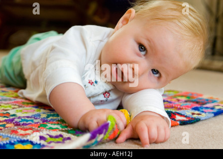 Chiudere orizzontale su ritratto di un periodo di sei mesi di età caucasian Baby girl rotolando sul pavimento Foto Stock