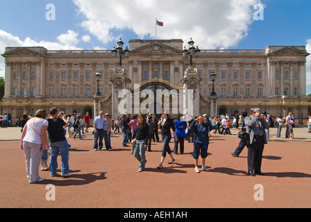 Orizzontale di ampio angolo di turisti al di fuori della parte anteriore del Buckingham Palace scattare fotografie in una giornata di sole. Foto Stock