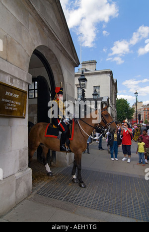 Vista verticale dell'elemento femmina della cavalleria della famiglia montato esternamente la sfilata delle Guardie a Cavallo circondato dai turisti per scattare le foto Foto Stock