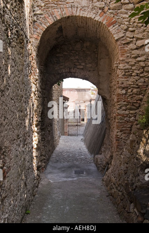 Un grande ingresso ad arco al tranquillo e pittoresco di ciottoli lapidato backstreet viuzze della città di Loano, Liguria Italia Foto Stock