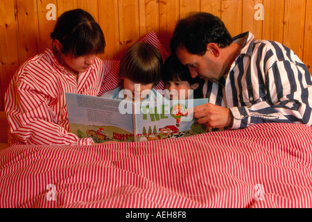 Famiglia la lettura di un libro per bambini in letto. Foto di Willy Matheisl Foto Stock