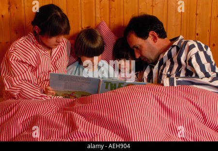 Famiglia la lettura di un libro per bambini in letto. Foto di Willy Matheisl Foto Stock