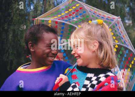 Ragazza 5-7 anni vecchia azienda per amico sorridente sul giorno di pioggia etnicamente diversi diversità etnica multiculturale multi culturale Myrleen MR Pearson Foto Stock
