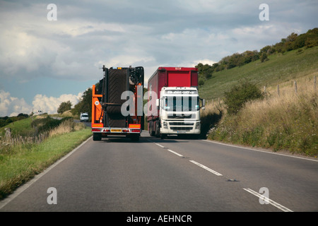 Due grandi autoveicoli pesanti adibiti al trasporto di merci in transito su una stretta English country road Foto Stock
