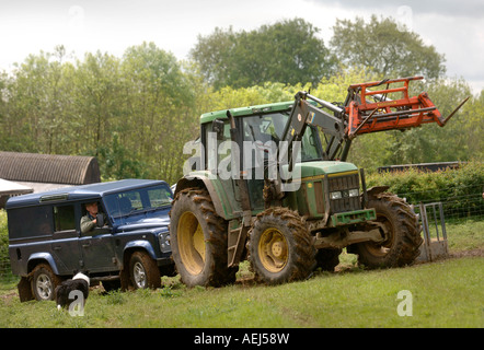 Un Allevatore ovino alla guida di un Land Rover Defender dietro ad un trattore su una GLOUCESTERSHIRE FARM REGNO UNITO Foto Stock