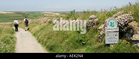 Il National Trust segno accanto a South West Coast Path walkers sul sentiero sulla collina sopra la Chiesa Cove vicino a Mullion Foto Stock