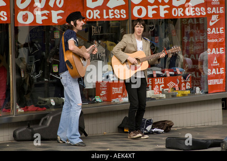 Due giovani artisti di strada su Sauchiehall Street, Glasgow, riproduzione di chitarre acustiche e il canto. Foto Stock
