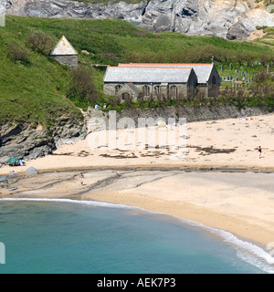 Chiesa Parrocchiale di San Winwaloe con cimitero & distaccata torre campanaria a Gunwalloe si accoccola accanto alla chiesa Cove Beach con persone godendo il sole Foto Stock