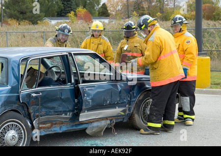 Fireman funziona con le ganasce della vita per estrarre la vittima di incidente automobilistico durante una sessione di formazione Foto Stock