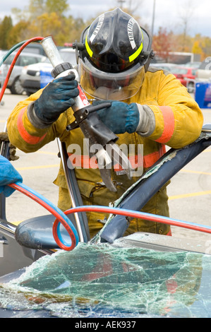 Fireman funziona con le ganasce della vita per estrarre la vittima di incidente automobilistico durante una sessione di formazione Foto Stock