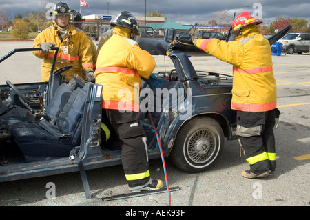 Fireman funziona con le ganasce della vita per estrarre la vittima di incidente automobilistico durante una sessione di formazione Foto Stock