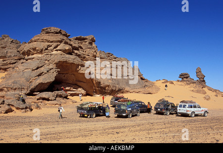 Libia Akakus, veicoli turistici da scogliera nel deserto del Sahara. I turisti alla ricerca di roccia preistorica arte dipinti Foto Stock