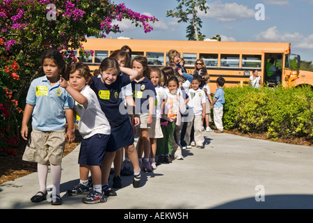 I bambini delle scuole americane allineando dopo scendere dal bus di scuola Foto Stock