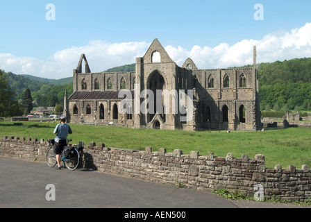 Tintern Abbey rovine del monastero nella valle del Wye, il Welsh banca del fiume Wye Monmouthshire Wales UK con ciclista ammirando la vista Foto Stock