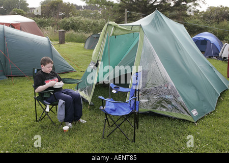 Ragazzo adolescente gustando la prima colazione camping tenda esterna sul campeggio Peel Isle of Man IOM Foto Stock