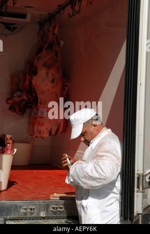 Macellaio in piedi nella parte anteriore del furgone con tela appeso all'interno. Andalusia Spagna Foto Stock