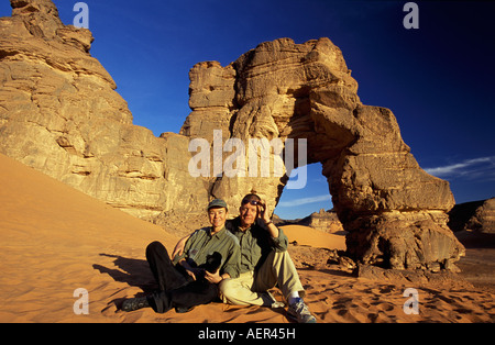 Libia Akakus scogliere nel deserto del Sahara, turisti in appoggio ad arco naturale chiamato Fezzenger. Circa 100 metri Foto Stock