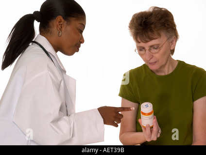 GP Africano Americano (25 - 30) che spiega la medicina di prescrizione a femmina superiore caucasica (età 60-70). Foto Stock