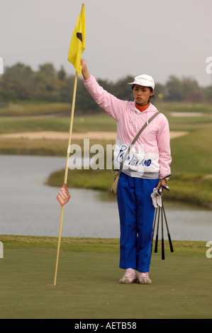Un partecipante golf caddy tenendo un flag pin su un verde in corrispondenza di un resort di golf nella provincia di Guangdong in Cina 2005 Foto Stock