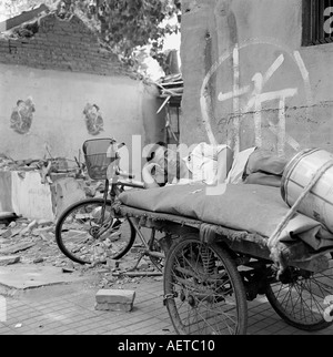 Un uomo dorme su una carriola in un hutong di Pechino che viene demolito 2003 Foto Stock