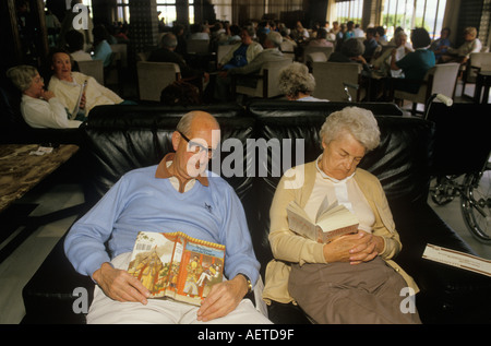 Libri di vacanza inglese anziani coppia addormentata. Giovane nel cuore Vacanze invernali al sole spagnolo. Isole Baleari Palma Nova Maiorca Spagna anni '1980 Foto Stock