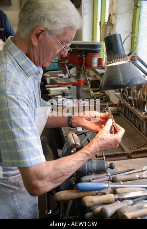 Stan Shaw presso il suo banco di lavoro esaminando un coltello da pesca Foto Stock