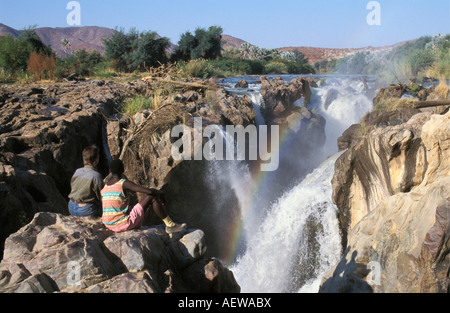 La Namibia, il Kaokoland a nord di Opuwo, turisti che si siedono vicino a Epupa Falls Foto Stock