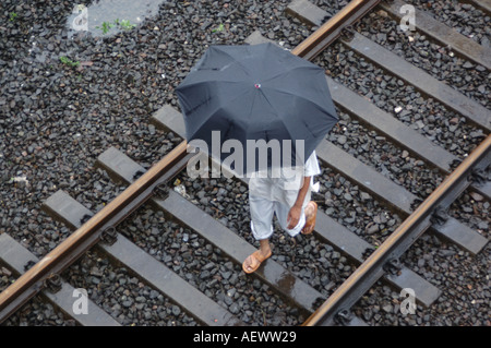 ANG71336 uomo a camminare sul binario ferroviario in un giorno di pioggia monsonica record mondiale la pioggia in Thane Maharashtra India Foto Stock