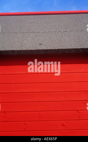 Dettaglio del rosso scarlatto di legno verniciato beach hut o un capannone o chalet o kiosk e tetto impermeabile sotto il cielo blu chiaro Foto Stock