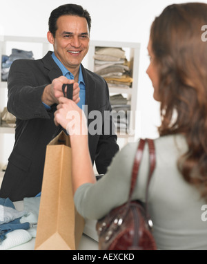 Addetto alle vendite maschio femmina ad assistere il cliente Foto Stock