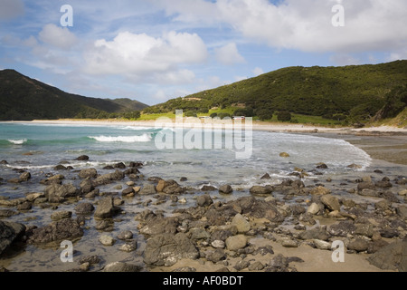 Tapotupotu deserta baia con spiaggia di sabbia le onde di laminazione rocce in primo piano e il promontorio roccioso del Pacifico sulla costa est della penisola Aupori Foto Stock