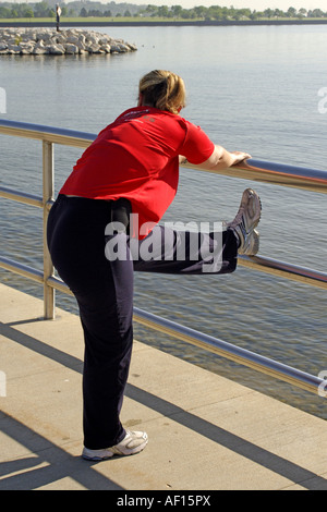 Donna di eseguire esercizi di stretching prima della sua corsa mattutina Foto Stock