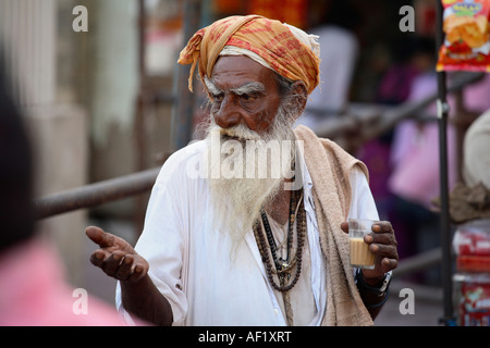 Anziano indiano che beve chai che mendono fuori del Tempio di Dwarkadhish, Dwarka, Gujarat, India Foto Stock