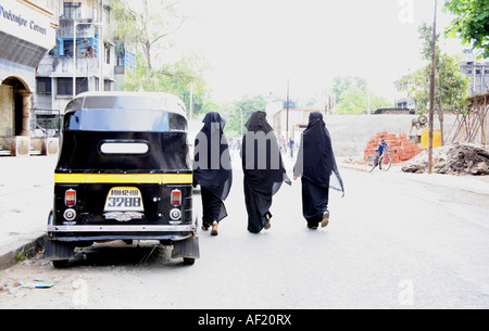 Tre femmine musulmane indiane che indossano niqab camminando lungo la strada, Pune, India Foto Stock