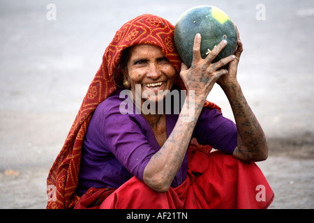 Rabari tribale femmina con tatuaggi a collo, braccio e mano che vendono meloni ad acqua allo stallo del mercato, una, Gujarat, India Foto Stock