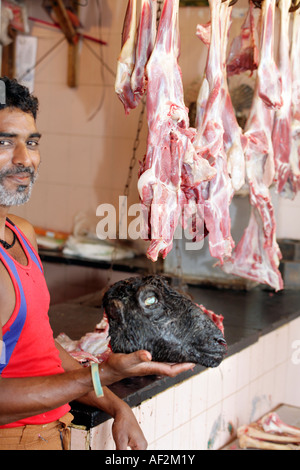 Macelleria Halal holding teschio di capra a retail store vendita di carni di montone e di pecora esclusivamente a base di carne. Margao Nuovo Mercato di Goa in India Foto Stock