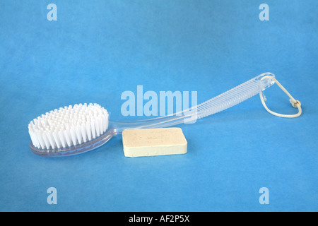 Bianco bagno di setole spazzola con manico chiaro sul retro con un piccolo fiocchi d'avena barra colorata di sapone nascosto nella curva della spazzola Foto Stock