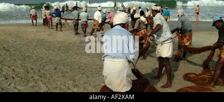 I pescatori sulla spiaggia Kovalam, Kerala, India meridionale, hall nelle reti di mattina presto. Foto Stock