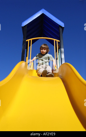 Ragazzo giovane andando verso il basso una diapositiva in un parco Foto Stock