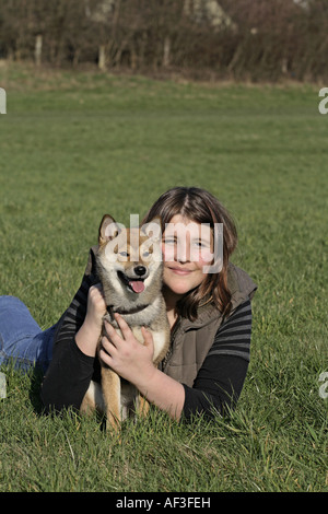 Shiba Inu (Canis lupus f. familiaris), con la giovane donna sul prato Foto Stock