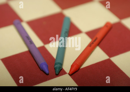 Orizzontale rossa, blu e rossa pastelli su un rosso e bianco sfondo checkerd Foto Stock