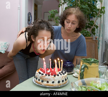 Madre e figlia come lei si brucia le candele sulla sua torta di compleanno al suo diciassettesimo compleanno MR Foto Stock