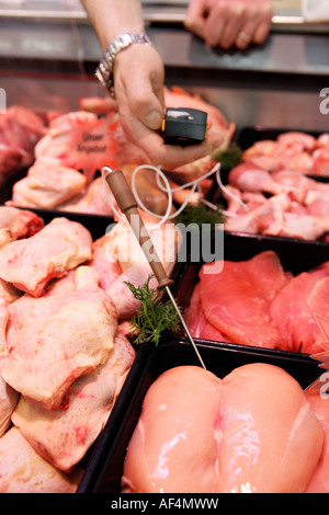 Controllo della qualità alimentare ispettore durante la misurazione della temperatura in un macellaio s shop in un supermercato Foto Stock
